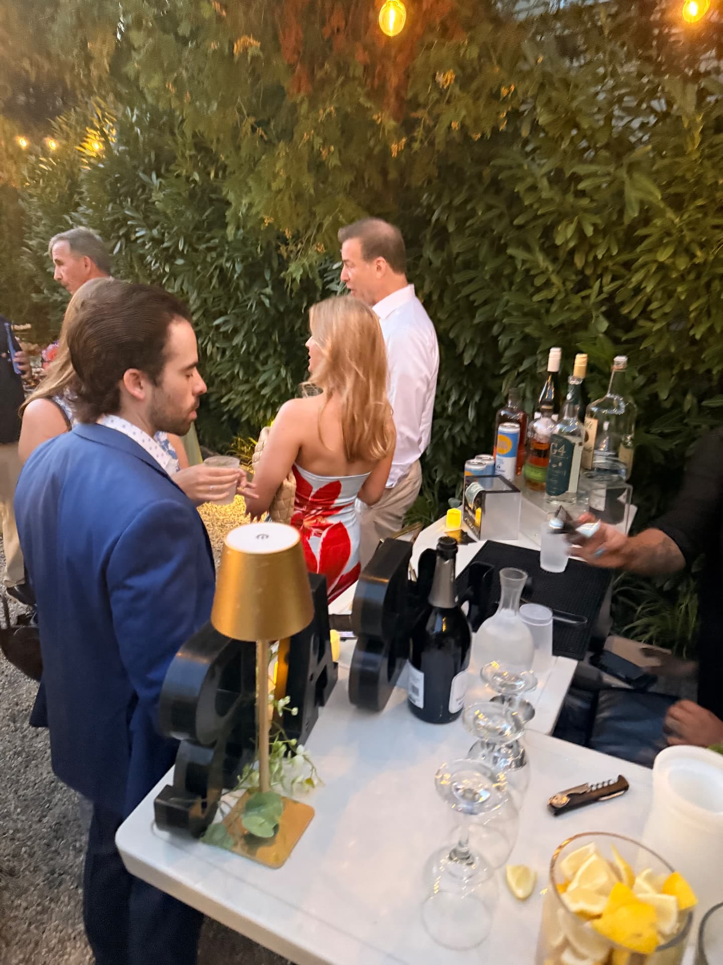 Wedding welcome party bar station with spirits, glassware and customized drinkware at dusk