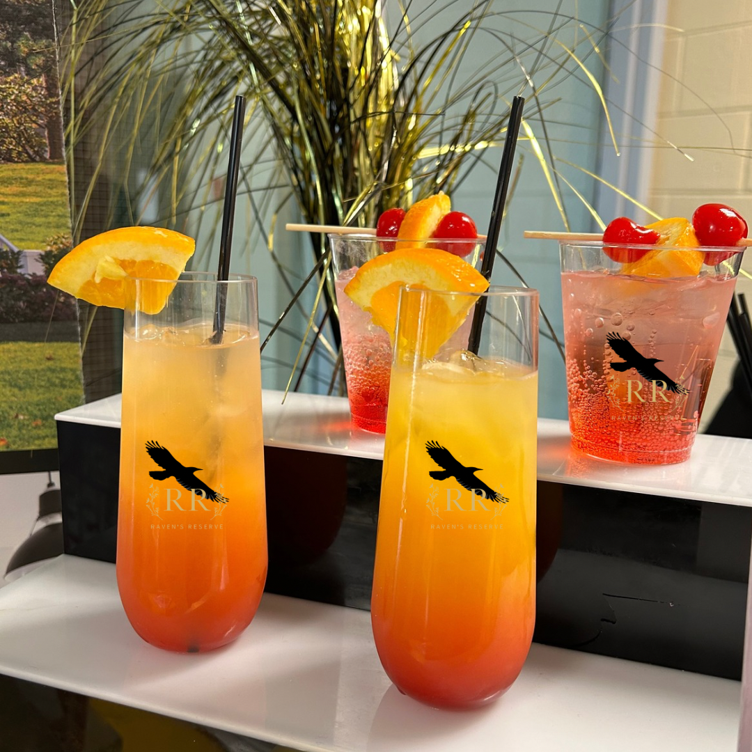 Raven's Reserve signature cocktails served in branded glassware with orange and cherry garnishes